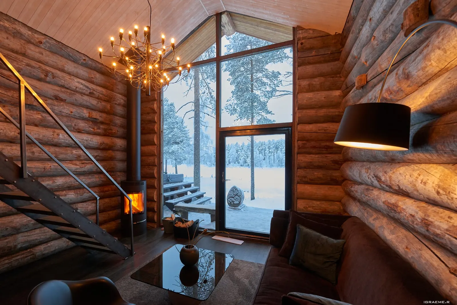 Fireside living room in a log cabin at Arctic Retreat, with a tall window onto snowy forest
