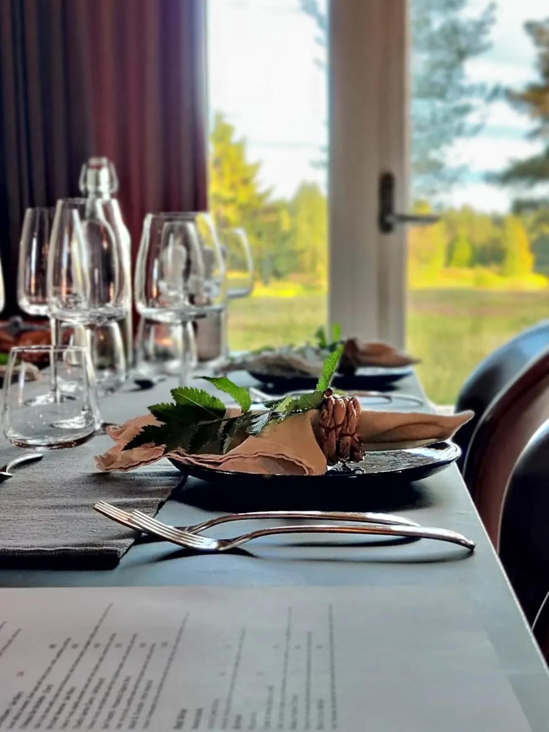 A Nordic dining table set by a window overlooking the forest